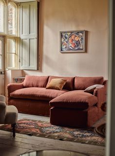 a living room scene with focus on the couch and chair in the foreground as well as an open window