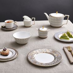 a table topped with plates and cups filled with food next to utensils on top of a cloth covered table