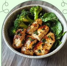 a bowl filled with chicken and broccoli on top of a wooden table