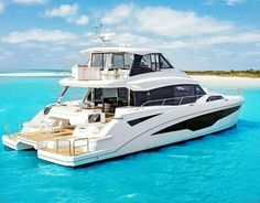 a white boat floating on top of the ocean next to a sandy beach and blue water