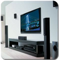 a flat screen tv mounted to the side of a wall next to speakers and an entertainment center