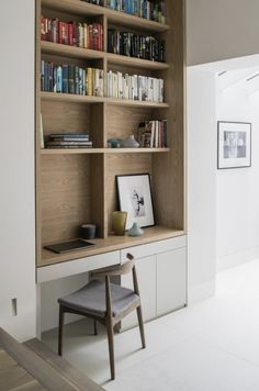 the bookshelf is full of books and there are two chairs in front of it