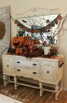 a white dresser topped with pumpkins and decorations