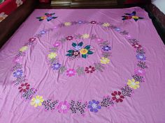 a pink bedspread with flowers on it and a circular design in the middle