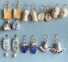 a collection of porcelain items hanging from hooks on a blue wall, including earrings and figurines