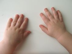 two hands reaching for something on a white counter top in front of a child's hand