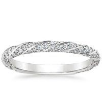 a white gold wedding ring with diamonds on the sides and an intricate design in the middle