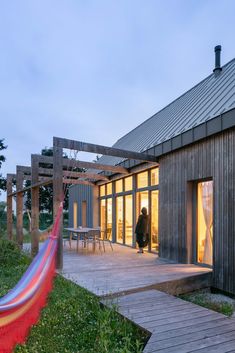 a person sitting in a hammock on top of a wooden deck next to a building