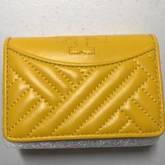 Leather. Gold Hardware. Keep Your Cash And Cards Securely Organized In Sophisticated Style With This Compact Wallet, Crafted From Sturdy Quilted Leather For Lasting Luxury. 4.46'' W X 3.15'' H X 1.5''D Leather Pin-Snap Closure Three Interior Slip Pockets Interior Card Slot Imported Color - Daisy Yellow Elegant Yellow Leather Wallet, Elegant Yellow Wallet, Yellow Coin Purse For Everyday Use, Yellow Leather Rectangular Wallet, Elegant Yellow Wallet With Card Slots, Daisy Yellow, Yellow Daisies, Compact Wallet, Tory Burch Bags