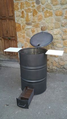 a large metal barrel sitting next to a stone building with a grill on it's side