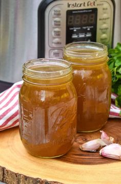 two jars filled with liquid sitting on top of a wooden table next to an instant pot