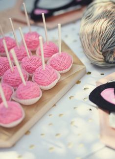 pink cupcakes are arranged on a wooden board with skewers in the shape of hearts