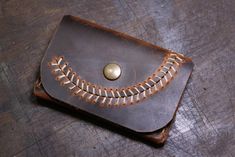 a leather wallet sitting on top of a wooden table next to a metal object with a button in it