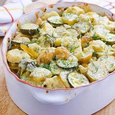 a casserole dish filled with zucchini and other vegetables on a wooden table