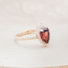 a close up of a ring with a stone on the top and diamonds around it