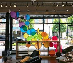 a room filled with lots of furniture and large glass windows that have colorful balloons hanging from the ceiling