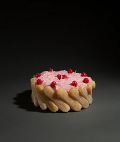 a cake with white frosting and raspberries on top, sitting on a black surface