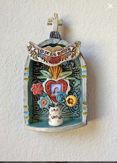 a ceramic wall hanging with an ornate frame and decorative decorations on the side of it