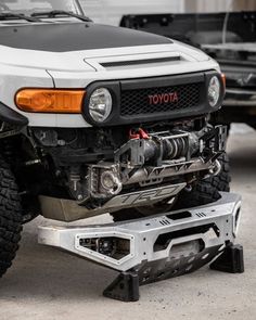 the front end of a white toyota pickup truck with its hood up on a lift