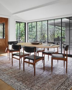 a dining room table with four chairs and a large rug in front of the window