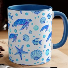 a blue and white coffee mug sitting on top of a wooden table next to a spoon