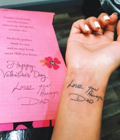 a woman's arm with a small tattoo on it and a pink card that says happy valentine's day