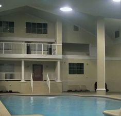 an indoor swimming pool with lounge chairs around it and two balconies on the second floor