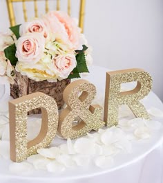 there is a cake with gold letters and flowers on the top one that says d & r