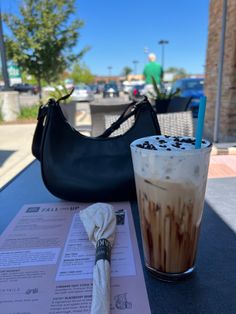 an iced drink with chocolate sprinkles sits on a table next to a purse