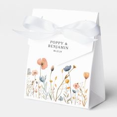 a white gift bag with flowers on it and a ribbon tied around the top that says poppy & benamain