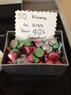 a box filled with candy sitting on top of a counter next to a sign that says 50 kisses to kiss your 40's goodbye