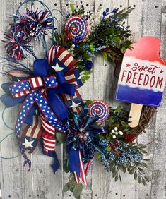 a patriotic wreath with popsicle shaped lollipops and flowers on a wooden fence