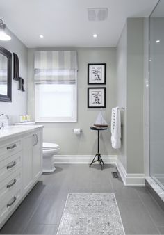 a white bathroom with gray tile flooring and walls, along with a walk in shower