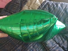 a person holding a green plastic bottle on top of a bed