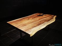 a wooden table sitting on top of a tiled floor next to a black tile wall