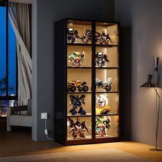 an illuminated display case filled with toys in a living room next to a large window