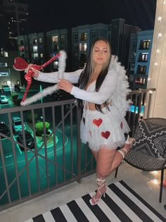 a woman in a white dress and red heart decorations on her arms, standing on a balcony