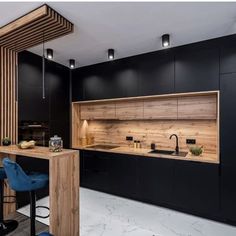 a kitchen with black cabinets and blue stools next to a counter top that has an island in the middle