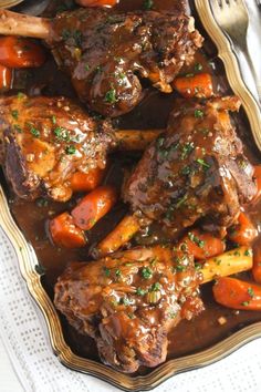 some meat with carrots and gravy on a plate next to a fork