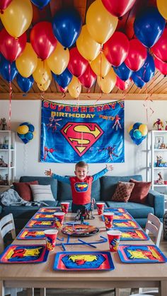 a young boy sitting at a table surrounded by birthday decorations and balloons that spell out his name