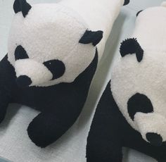 two black and white stuffed panda bears laying down