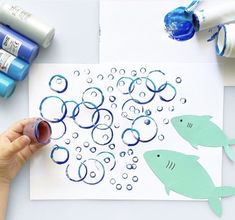 someone is making an art project with watercolors on paper and glue for the fish