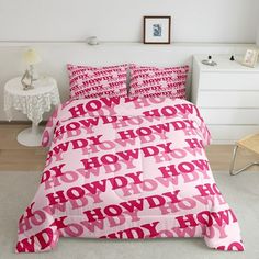 a bed with pink letters on it in a white room next to a table and chair