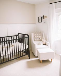 a baby's room with a crib, chair and window