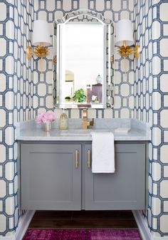 a bathroom with blue and white wallpaper on the walls, two sinks and a mirror