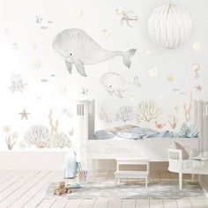 a child's room decorated in white and blue with sea animals on the wall