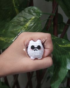 a hand holding a small white crocheted owl