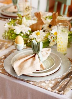 the table is set for easter dinner with bunny napkins and place settings on it