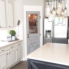 a kitchen with white cabinets and an island in front of the door that leads to another room