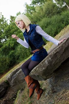 a woman with blond hair is leaning on a rock and posing for the camera while wearing boots